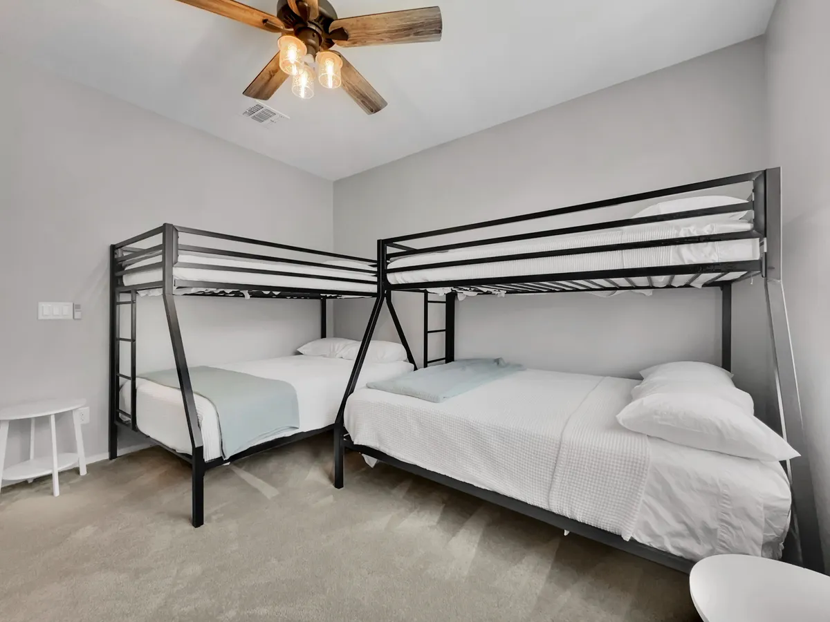 A cheerful bunk room with sturdy bunk beds, soft bedding, and a ceiling fan. The relaxed atmosphere makes it ideal for kids or groups, with plush linens and a playful, family-friendly vibe perfect for sleepovers and fun nights.