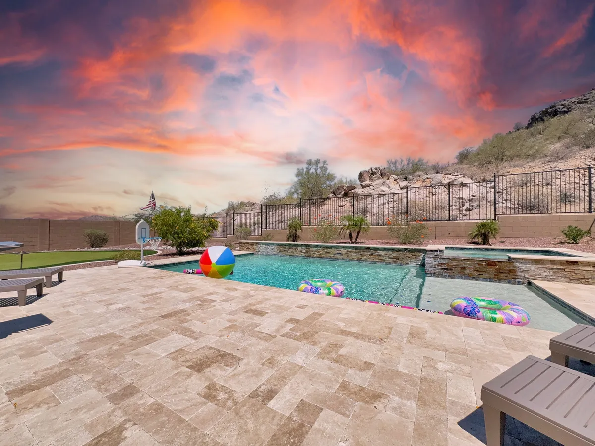 A joyful exterior scene with a sparkling swimming pool, colorful beach ball and pool floats, and majestic mountains rising in the background. The atmosphere is lively and carefree, emphasizing the fun and relaxation available outdoors.