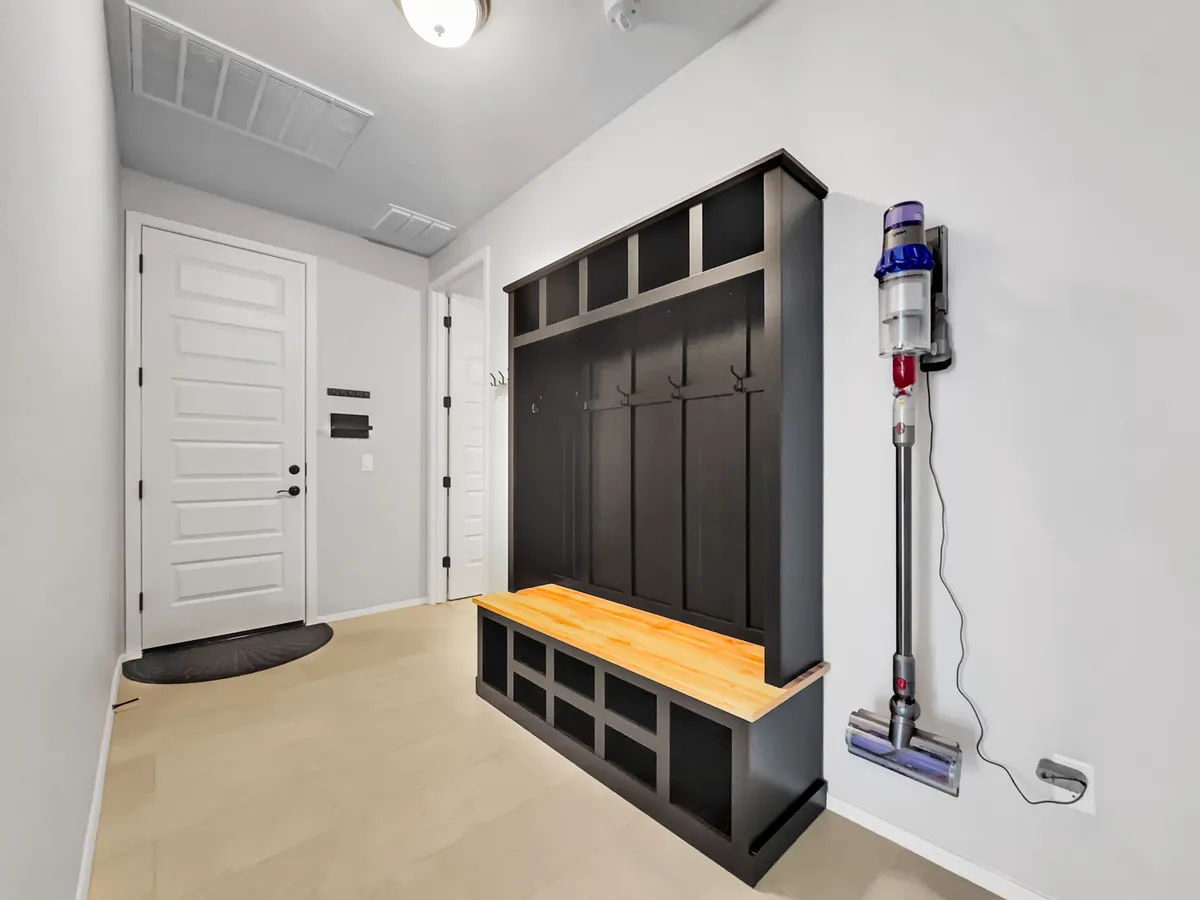 A practical mudroom scene with a bench, coat hooks, and the front door. This area is designed for easy transitions between home and outdoor excursions, symbolizing the start and end of local adventures.