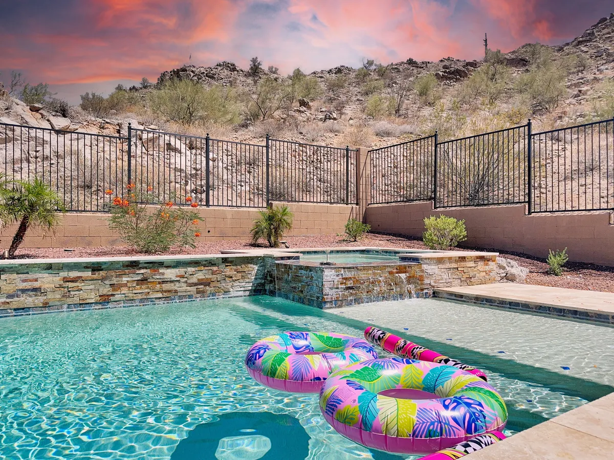 This image showcases a sparkling swimming pool adorned with colorful floaties, set against a breathtaking mountain backdrop and surrounded by a landscaped garden. The inviting pool area is ideal for sunbathing, swimming, and relaxing with friends or family while taking in the mountain views.