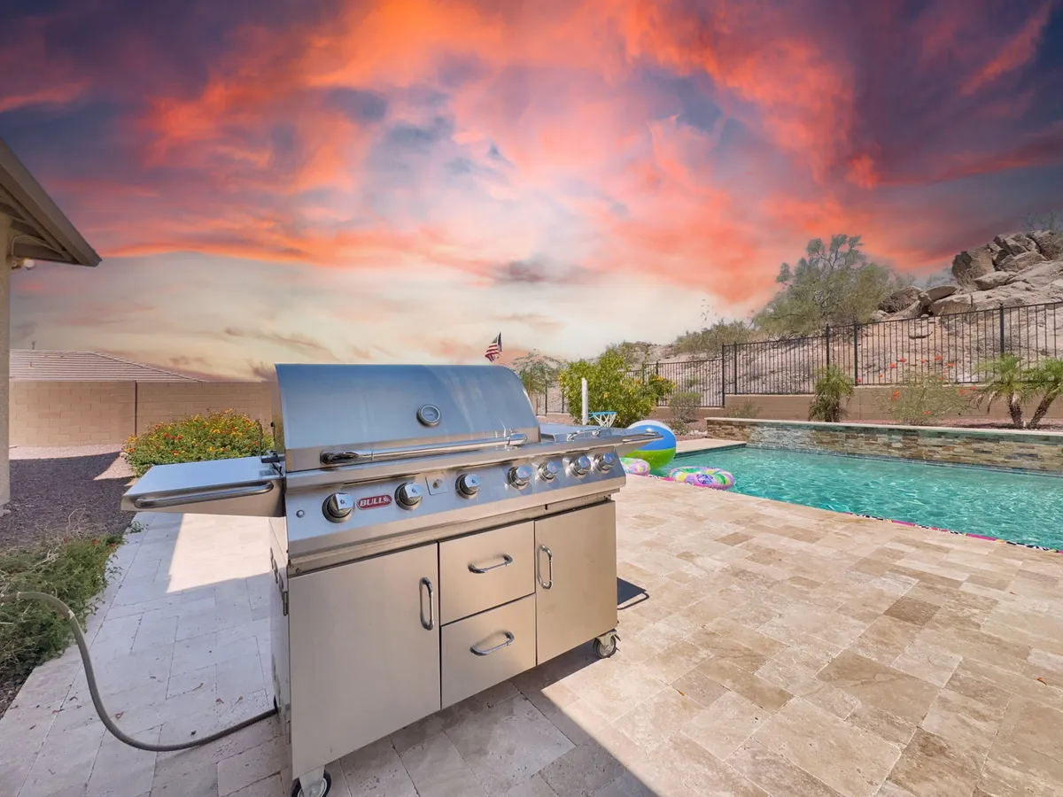 This exterior image centers on a barbecue grill near the pool, highlighting a relaxed setting for preparing meals and socializing. The scene emphasizes the integration of grilling, poolside lounging, and enjoying the outdoors under open skies.