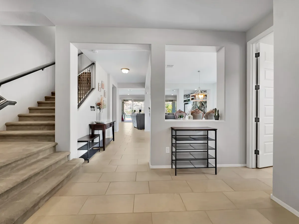This image features a bright and open entryway with a staircase and console table, flooded with natural light. The space feels welcoming and hints at the home's connection between interior comfort and the world outside.